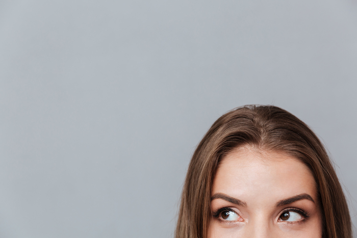 Cropped image of face of woman looking aside. Isolated gray background