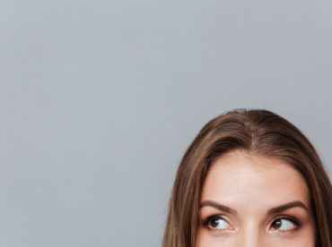 Cropped image of face of woman looking aside. Isolated gray background