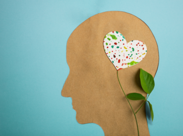 recorte de papel pardo em forma de rosto, com um raminho de flor onde as pétalas são um coração de pano, ilustra artigo sobre saúde mental e saúde ocular
