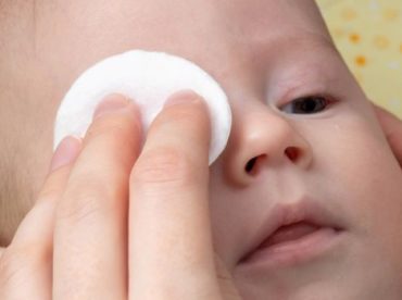 rosto de bebê caucasiano com um dos olhos tampados por um algodão para ilustrar artigo sobre teste do olhinho