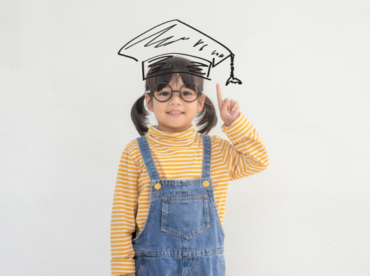 menina oriental de óculos e com desenho de um chapéu de formatura ilustra post sobre check-up ocular na idade escolar